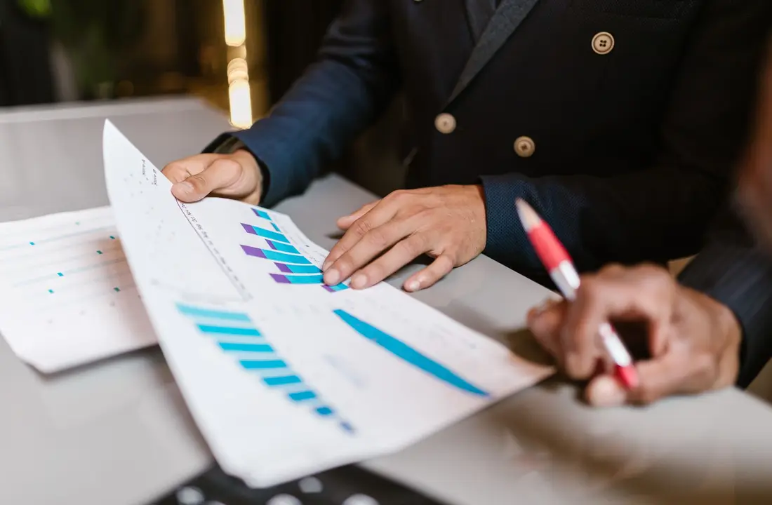 Close-up of professionals reviewing financial graphs at a business meeting.